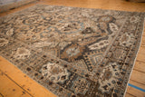 Angled view of a vintage Khoy carpet's geometric cartouche border and abrashed field.