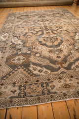 Angled view of a distressed Khoy rug showing its time-softened neutral tones and flowing design.