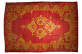 Antique Oushak carpet with a geometric medallion cluster in saffron and gold on a dusty cochineal red field.