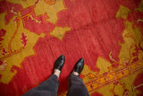 Close-up of the antique Oushak carpet's short pile and texture in dusty cochineal red and gold.