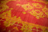 Low pile texture and large-scale saffron yellow motifs on the cochineal red field of an antique Oushak carpet.