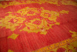A view across the short pile of an antique Oushak, detailing the saffron and cochineal red medallion pattern.