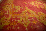 Angled perspective of an antique Oushak carpet's corner in dusty red and saffron yellow tones.