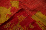 Corner view of an antique Oushak showing its hand-knotted back, red pile, and side selvage.