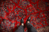 The plush cherry red pile of a vintage Kazvin carpet showing detailed floral patterns in navy and powder blue.