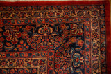 Corner detail of a vintage Kazvin carpet showing intricate floral borders in red, navy, and beige.