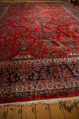 A low angle across the vintage Kazvin carpet's red field and intricate navy blue floral border.