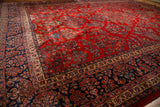 Vintage Kazvin carpet's plush red floral field and intricate navy border from a low angle.