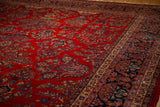 Angled detail of a vintage Kazvin carpet's cherry red field and intricate navy floral border.