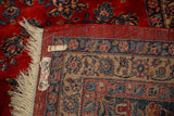 Corner of a vintage Kazvin carpet showing the hand-knotted back, red pile, and intact fringe.