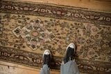 Distressed texture and floral design of a vintage Persian runner with pink, blue, and brown accents.