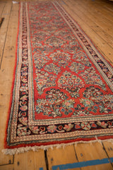 Angled view down the length of a vintage Sarouk runner, showing its cherry red field and floral sprays.