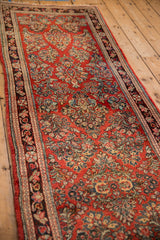Angled view of a vintage Sarouk runner highlighting its intricate floral pattern on a cherry red field.