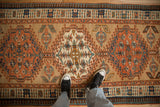 A detailed look at the terracotta medallions and geometric pawn border on an antique Serab runner.