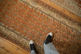 Repeating plant patterns and a colorful barber pole border on a distressed Persian runner.