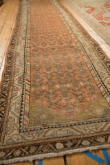 Low angle view down the length of a distressed vintage Malayer rug runner showing its faded colors.