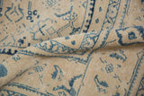 Soft fold revealing the distressed, low-pile texture and dusty blue motifs of a vintage Mahal carpet.