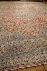 Distressed Persian Meshed rug with intricate border design, sprawling vines, and soft cherry red and slate blue colors.