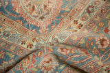 Distressed vintage Meshed carpet showcasing faded floral vines, blue, red, and beige texture.
