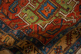 The textured, low-cut wool pile of a folded antique Heriz rug runner with geometric patterns.