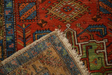 Folded corner of an antique Heriz rug displaying the hand-knotted construction, side selvage, and fringe.