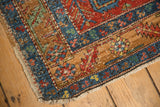 A dog-eared corner of an antique Heriz runner showing wear across its geometric border.
