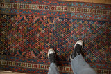 The repeating lattice of germinating blossoms on a colorful hand-knotted Persian Kurdish runner.