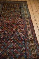 Angled view of a vintage runner showing the trefoil blossom pattern and detailed geometric border.