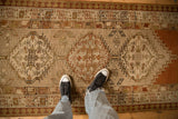 A down-angle view of a distressed Serab runner's earthy toned medallions and worn pile.