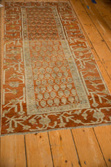 A view down the length of a distressed Hamadan runner in terracotta and ivory.