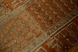 Close-up on the distressed texture of repeating botehs and the wide geometric border of a Hamadan runner.