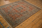 Angled view of a vintage Bijar rug's rust-red Herati field and geometric turtle motif border.