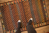 Underfoot view of antique Caucasian rug, featuring rainbow-like germinating blossoms and geometric border.