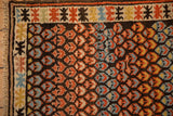 Antique Caucasian rug corner showing dark field with staggered germinating blossoms and geometric border.