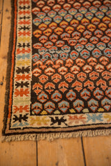 Geometric border and staggered madder, blue, yellow germinating blossoms on an antique Caucasian rug.