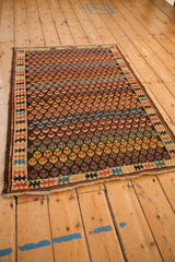 Staggered germinating blossoms in rainbow colors on an antique Caucasian rug with geometric border.