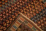 Corner detail of an antique Caucasian rug, showing germinating blossoms, geometric border, and fringe.
