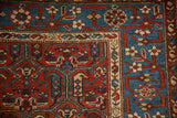 Corner of an antique Kurdish rug showing its sky blue pomegranate border and intricate red field.