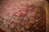 Vintage Sarouk carpet border with dark scrolling floral motifs and cherry red field.