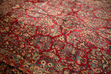 Cherry red Sarouk carpet field with ivory, dusty teal, and blush floral vines.