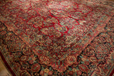 Vintage Sarouk carpet: cherry red field, dark floral border, dusty teal stripe detail.