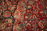 Intricate floral spray on contrasting dark and cherry red vintage Sarouk carpet.