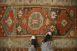 Looking down at the heavy abrashes and worn texture on a distressed Persian Malayer rug.