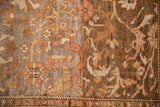 Distressed Malayer carpet close-up: heavy abrashes on coffee brown and dusty gold vines.