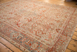 Angled view of a distressed Heriz carpet's terracotta field and Turtle Samovar motif border.