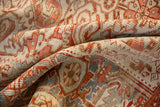 Close-up on the textural, hand-knotted weave of a distressed Heriz rug in terracotta and silver.