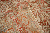 Folded corner of a vintage Heriz carpet showing its hand-knotted back and secured side cord.