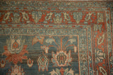 Detailed corner of a distressed Persian rug showing floral borders in dusty teal and madder red.