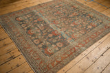Angled view of a distressed Bibikabad carpet with an allover floral pattern in abrashed teal and terracotta.