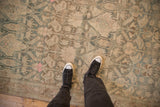 A close view of a distressed Bijar carpet's low-pile texture and muted pattern with dusty teal and pink.